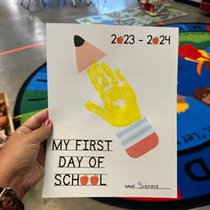 a person holding up a handprinted card with the words my first day of school