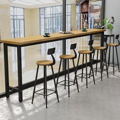 a bar with four stools in front of it and a plant on the counter