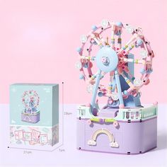 a toy ferris wheel next to a box on a pink background with other toys in it