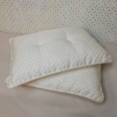 two white pillows sitting next to each other on a bed