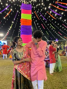 two people standing next to each other in front of a pole with lights on it