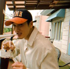 a man sitting at a table with a drink in his hand and wearing an orange hat