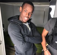 a man standing next to another man in a small room with backpacks on his back