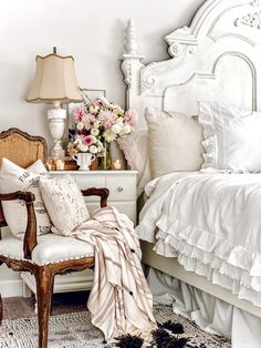 a bedroom with white furniture and flowers in vases on the nightstand next to the bed