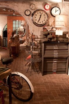 there are many clocks on the wall in this room and one has a bicycle parked next to it