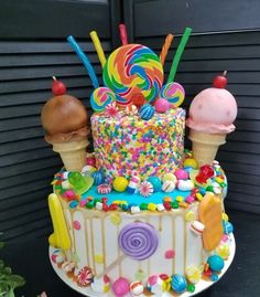 a multi layer cake decorated with candy, lollipops, and ice cream