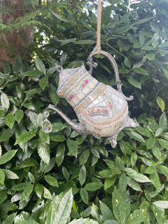 a decorative teapot hanging from a tree