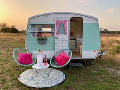 an rv is parked on the grass with two chairs and a table in front of it