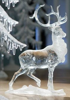 a glass deer figurine sitting on top of a table next to a christmas tree