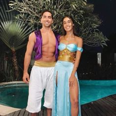 a man and woman in costume standing next to a pool