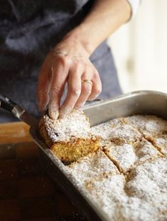 a person in an apron is cutting some food into small squares on a baking pan