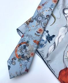 An unusual Silk Twill Tie and coordinating pocket square or little scarf with x-ray crab and tulip design. The 'Evolution' Tie and pocket square with a pale blue ground, features vintage style illustrations created by hand and digitally printed onto high quality silk. The unique design was inspired by the infinite complexities of nature and the fascinating theory of evolution with details including scientific illustration style tulips and x-ray image of a crab, moths and pineapples. The colour p Rectangular Pocket Square As A Gift, Elegant Pocket Square Gift, Elegant Rectangular Pocket Square As Gift, Blue Tie With Pocket Square As Gift, Summer Pocket Square For Suit And Tie As Gift, Summer Gift Pocket Square For Suit And Tie, Summer Gift Pocket Square Suit Accessories, Blue Ties With Pocket Square For Wedding, Blue Pocket Square For Wedding