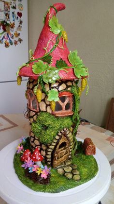 a small house made out of grass and rocks on top of a white cake plate