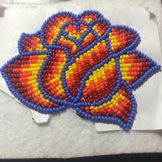 the beaded flower is sitting on top of tissue paper and it's colorful