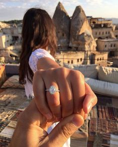 a woman is holding up her engagement ring