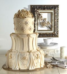 a three tiered wedding cake sitting on top of a table next to a mirror