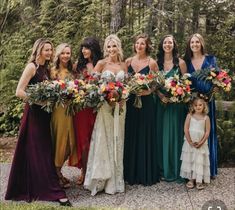 a group of women standing next to each other holding bouquets in their hands and smiling at the camera