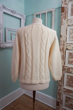 A classic women's cardigan sweater, in a soft ivory white acrylic. It has a unique wide pattern of traditional cable knit down the front. It closes up the front with a row of really unique swirly plastic buttons. The sweater is soft and comfy, not stiff at all. No damage or issues. Please check measurements carefully. Condition: Very Nice Vintage Tag: 100% Acrylic Size L Measurements in inches.... Length: 23.5 Chest: 19 ✩ Because you don't want to miss a thing, follow @heartkeyologie on Facebook Classic Crew Neck Cable Knit Cardigan, Cream Cable Knit Crew Neck Outerwear, Classic White Textured Knit Cardigan, Classic Beige Cable Knit Cardigan, Classic Cream Crew Neck Cardigan, Classic Cream Cable Knit Cardigan, Cream Fitted Knitted Sweater, Fitted Cream Knitted Sweater, Winter Cable Knit Pattern In Cream