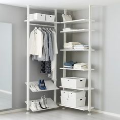 an open white closet with clothes and shoes on shelves in the corner, next to a mirror