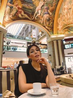 a woman sitting at a table with a cup and saucer in front of her