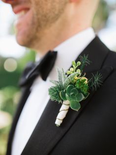 a man in a tuxedo wearing a boutonniere with succulents and greenery