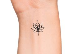 a small lotus flower tattoo on the left side of the wrist, with an arrow in the center