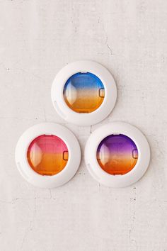 three white lights with multicolored lenses are on the wall next to each other