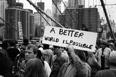 a group of people standing around each other holding signs that read a better world is possible