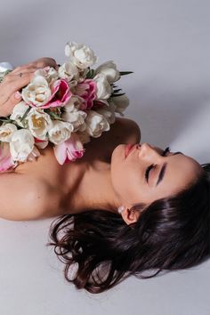 a woman laying on the ground with flowers in her hair