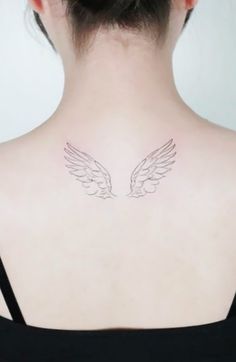 the back of a woman's neck with two white wings on it