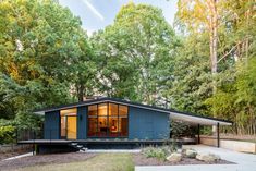 a small blue house surrounded by trees in the woods