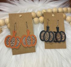 three pairs of leopard print and orange hoop earrings on top of a white fur rug