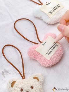 three small teddy bears are being held by someone's hand while they have tags attached to them