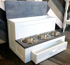 three bowls are sitting in the middle of a white cabinet with drawers on it and one is empty