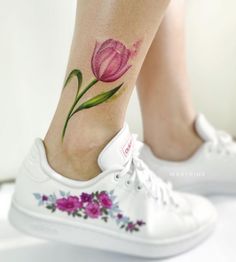 a close up of a person's foot with a flower tattoo on the ankle