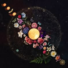 a lit candle surrounded by flowers on a black surface with candles in the background art print