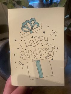 a hand holding up a birthday card that says happy birthday with a present on it