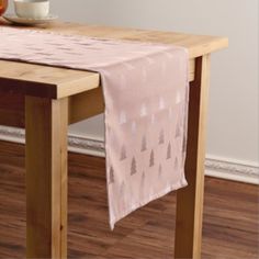 a table with a pink flowered cloth on it and a bowl of oranges in the background