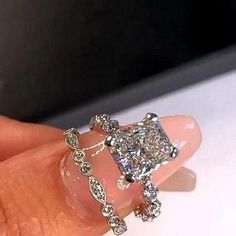 a woman's hand with a diamond ring on top of her finger and an engagement ring in the middle