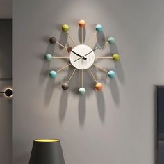 a clock that is on the wall next to a table with a lamp in front of it