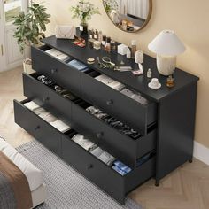 a black dresser with drawers and mirror above it