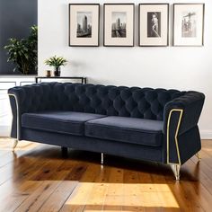 a blue couch sitting on top of a wooden floor next to two framed pictures above it