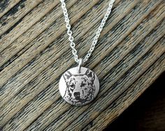 a necklace with a dog's head on it sitting on top of a wooden table