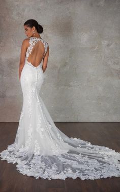 a woman in a white wedding dress with an open back and floral appliques