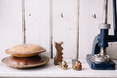 an old fashioned machine and other items on a shelf in front of a white painted wall