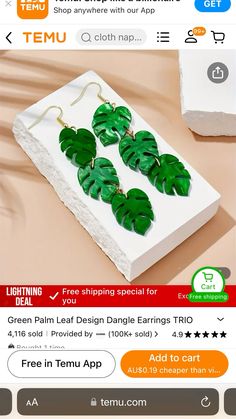 a pair of green leaf dangle earrings on top of a white box with an ad for temu