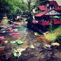 there are many people on inflatable rafts floating down the river near a house