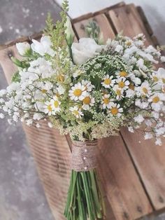 a bouquet of daisies and other flowers in a vase on a wooden table top