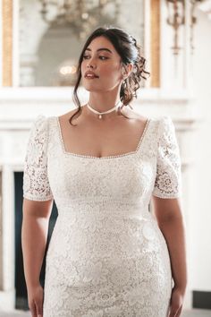 a woman in a white dress is posing for the camera with her hands on her hips