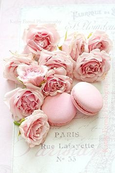 pink roses and macaroons are on top of an old french postcard with the eiffel tower in the background